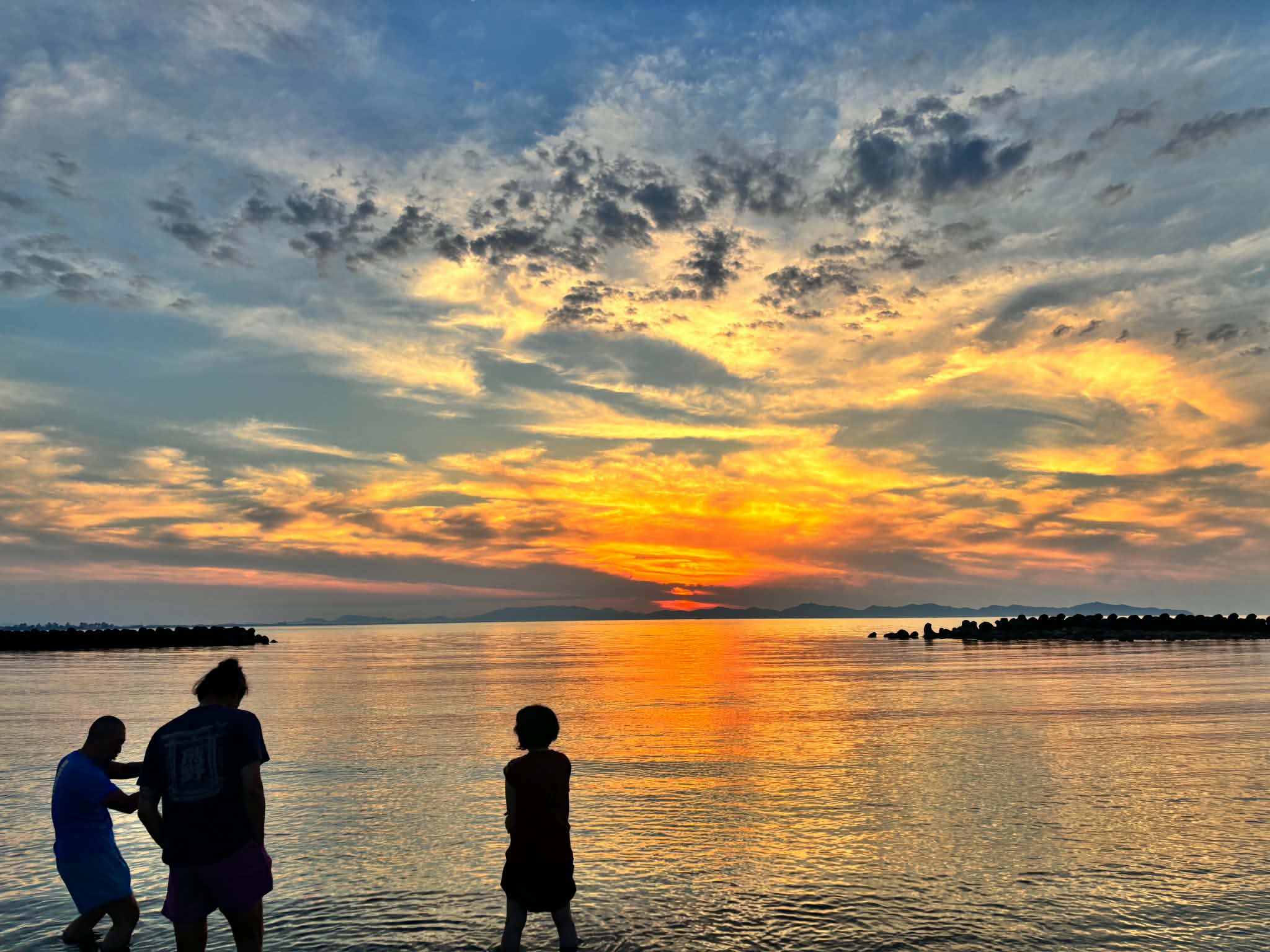 夕日に染まる海に入る人たち